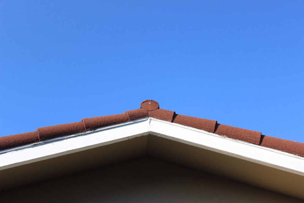 The roof of a house with blue sky above it.