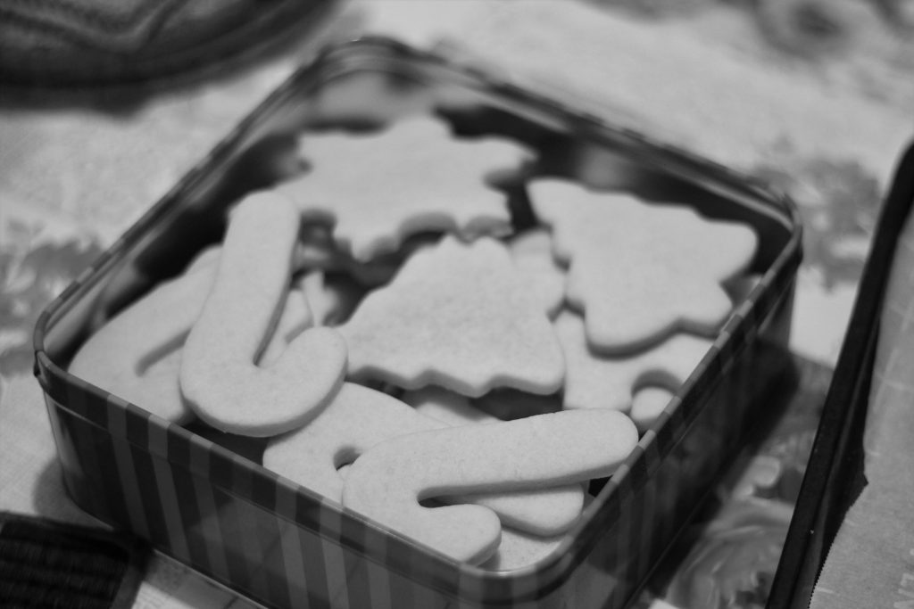 A tin of Christmas themed cookies like candy canes, Christmas trees, and snowflakes.