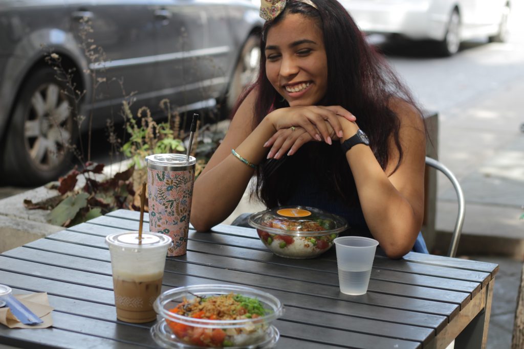 This photo represents something that gives me warmth: getting lunch and coffee with my best friend. The photo shows my best friend smiling at a table with food. 