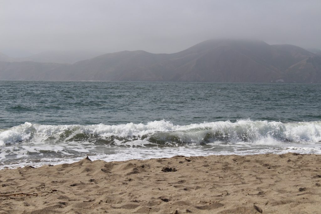 Photo of a landscape to show symmetry. The photo shows waves on a beach with mountains in the background.