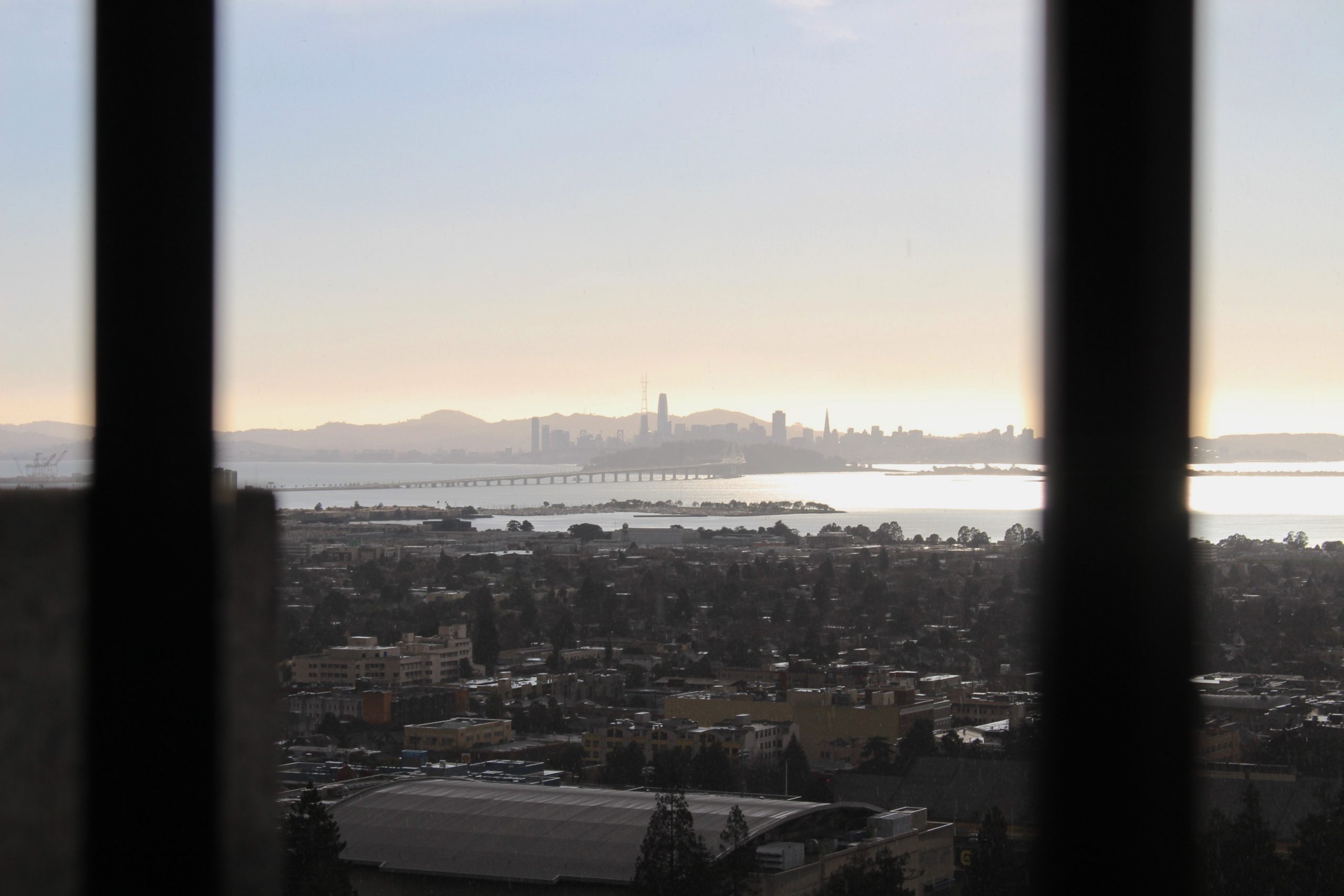 Photo of the city of Berkeley from the view of the Campanile Tower. A sunset over the buildings is pictured.