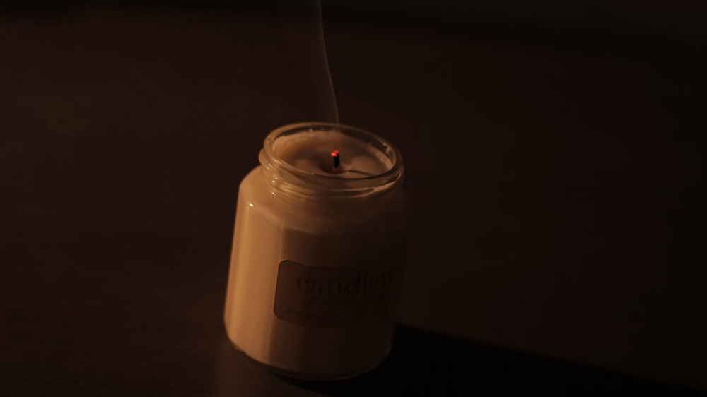 This is an photo of a candle that has recently gone out and has smoke trailing from the wick.