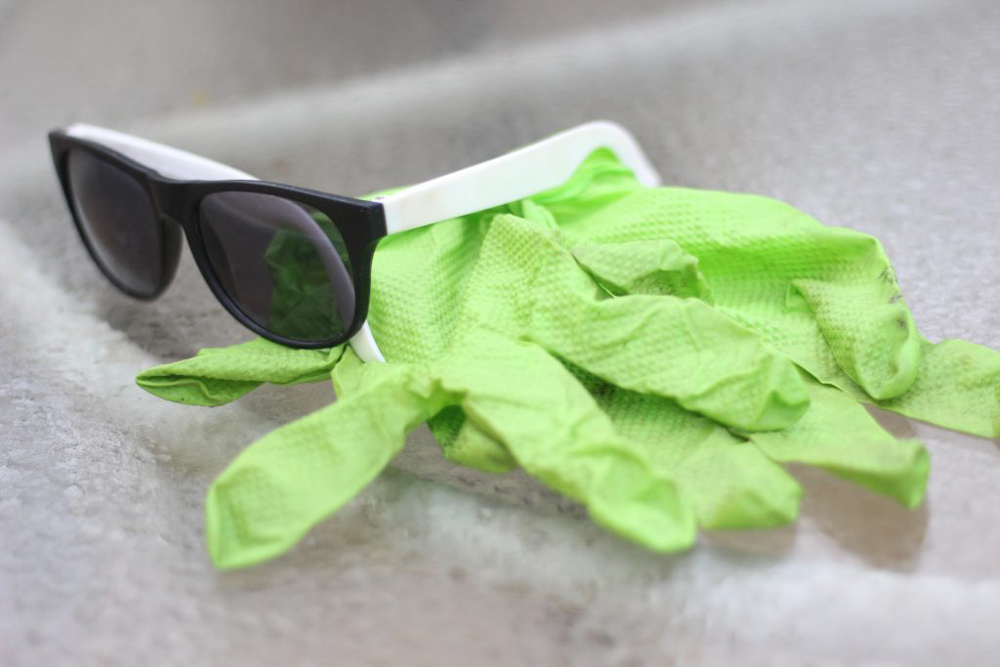 a cheap pair of sunglasses on a pair of green rubber gloves