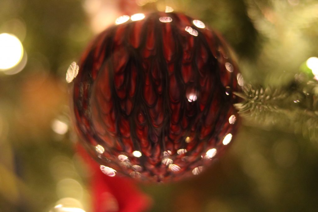 A photo of a bauble on a Christmas tree with red, firey designs.  The background is very blurred out.