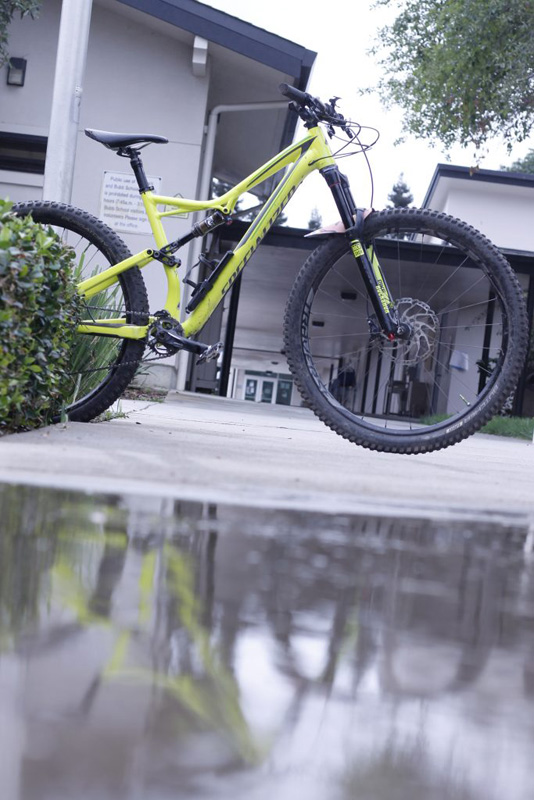 A vertical photo showing a bike in a hallway and its reflection in a puddle at the bottom of the picture.