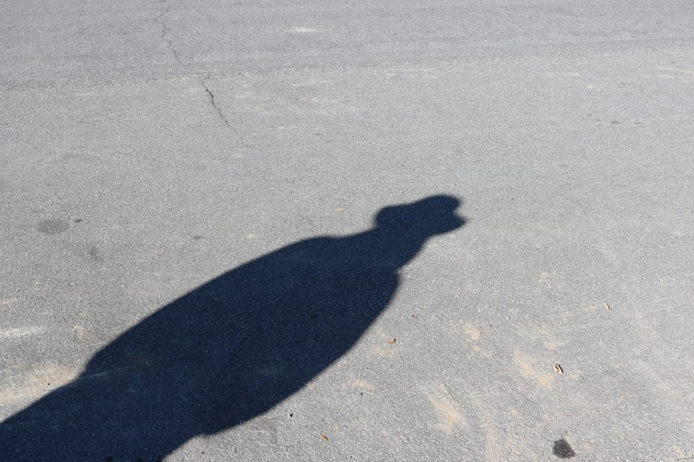 The shadow of a person in a hat and coat.