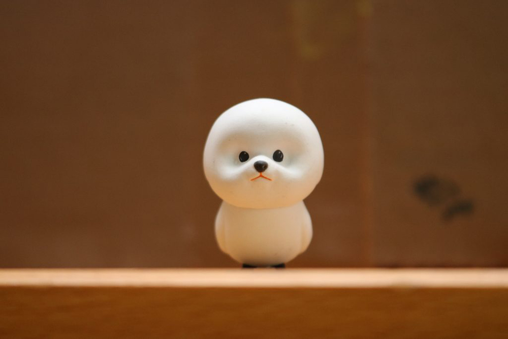 A small toy standing on a wooden shelf.