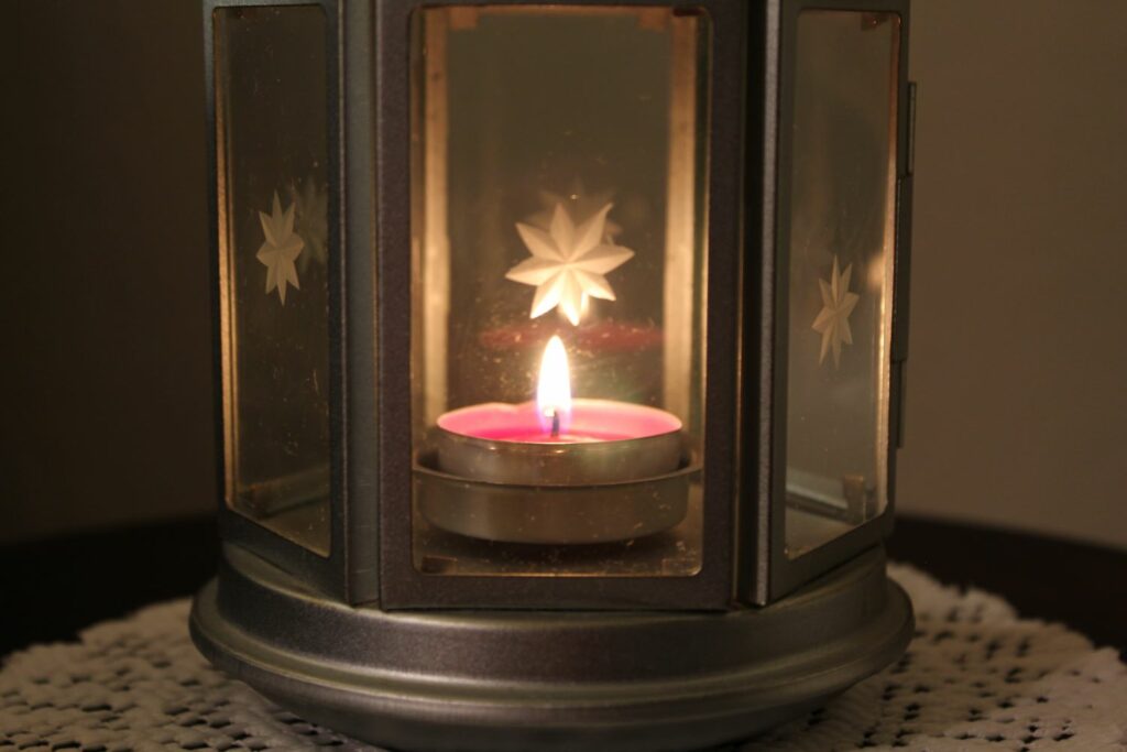 a tealight candle inside a glass lantern in a dark room