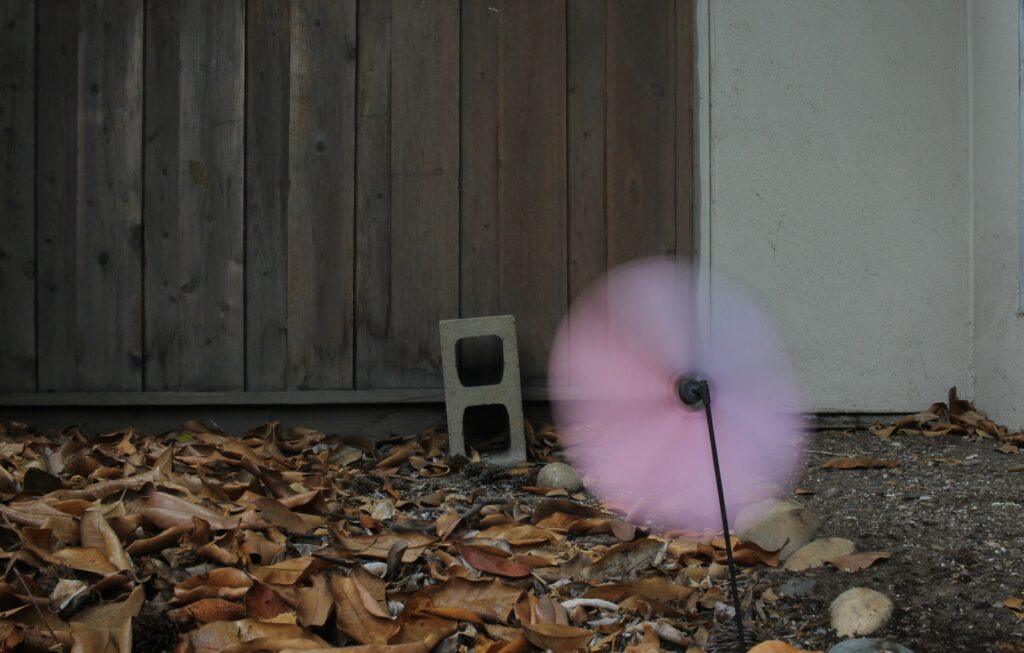 A light pink and purple pinwheel spinning in the wind