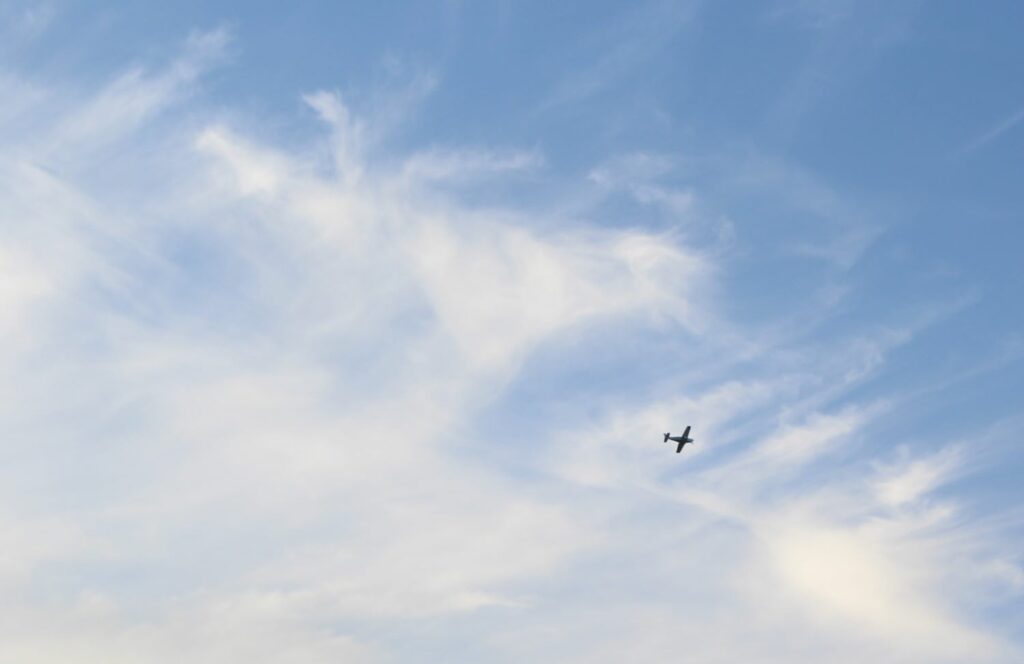 a small black plane surrounded by blue sky and white clouds