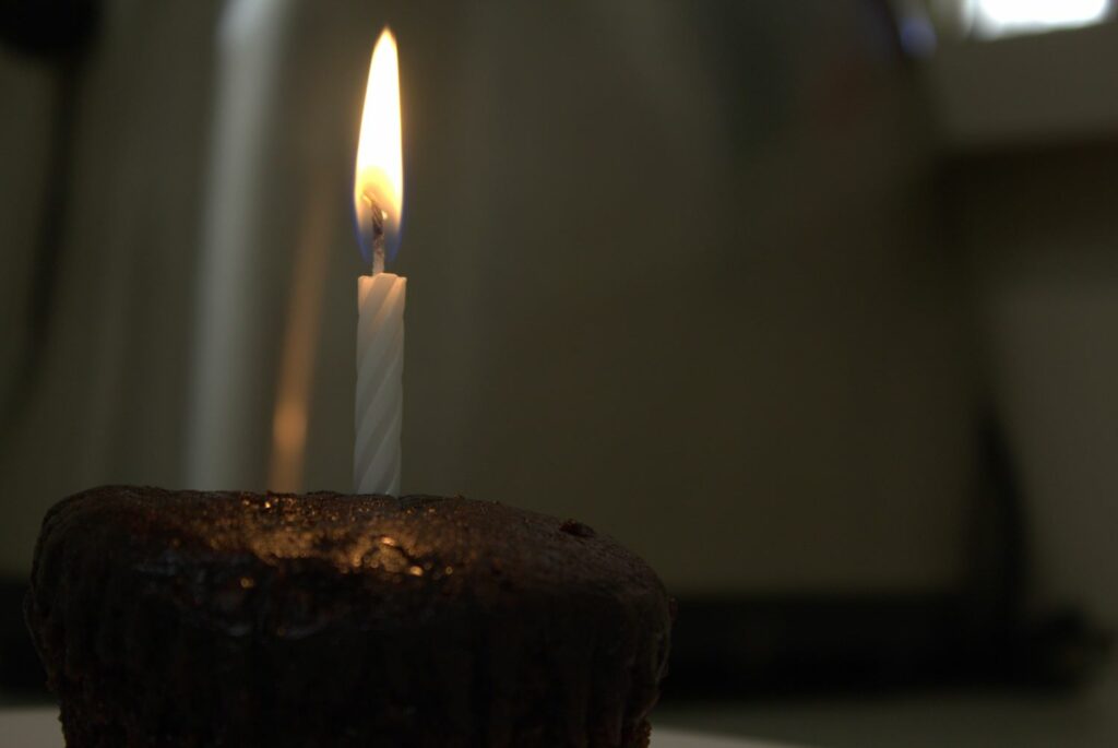 a white candle on a chocolate cupcake