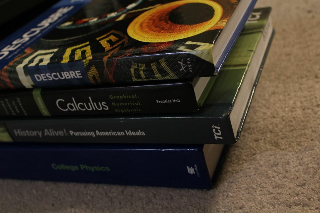 a stack of textbooks (specifically spanish, calculus, history, and physics)