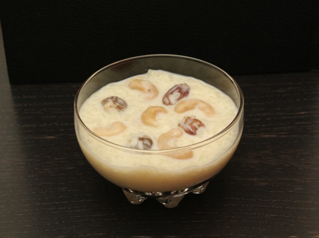 rice pudding in a glass bowl topped with raisins and cashews