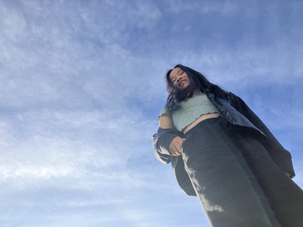 a person standing up with the blue sky behind her