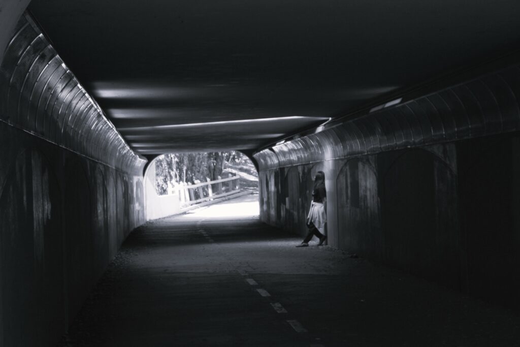 black and white photo of a person standing alone inside a tunnel