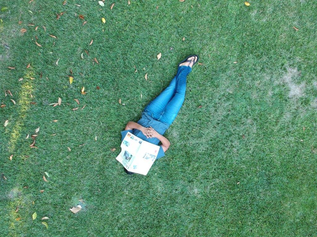 A self portrait that was taken without showing my face. The photo is a birds-eye of me laying on grass, asleep, with an Oracle over my face.