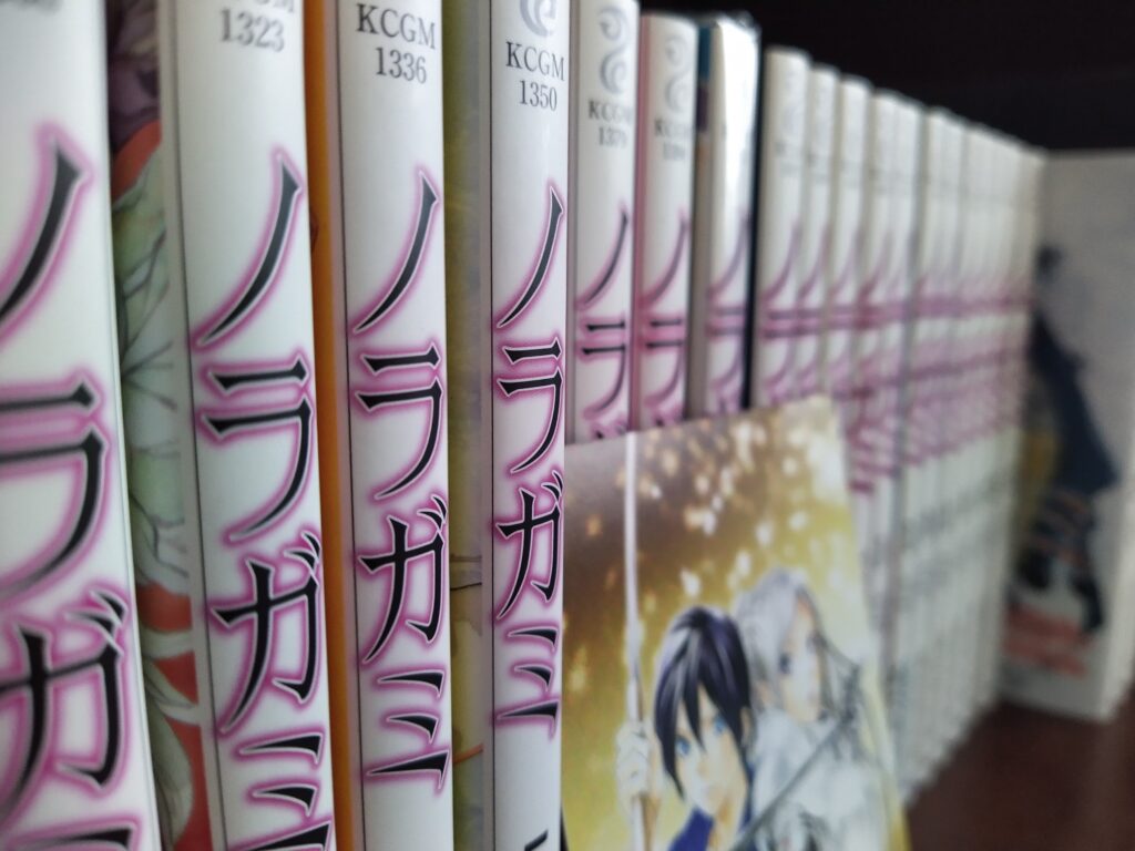 A bunch of manga volumes. The manga near the camera is in focus, while the manga is the back is out of focus. The series in Noragami.