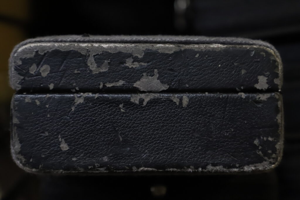 photo of one end of a worn out leather bow case