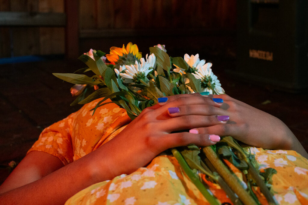 A close up of a person laying down holding a bouquet, their face is blocked