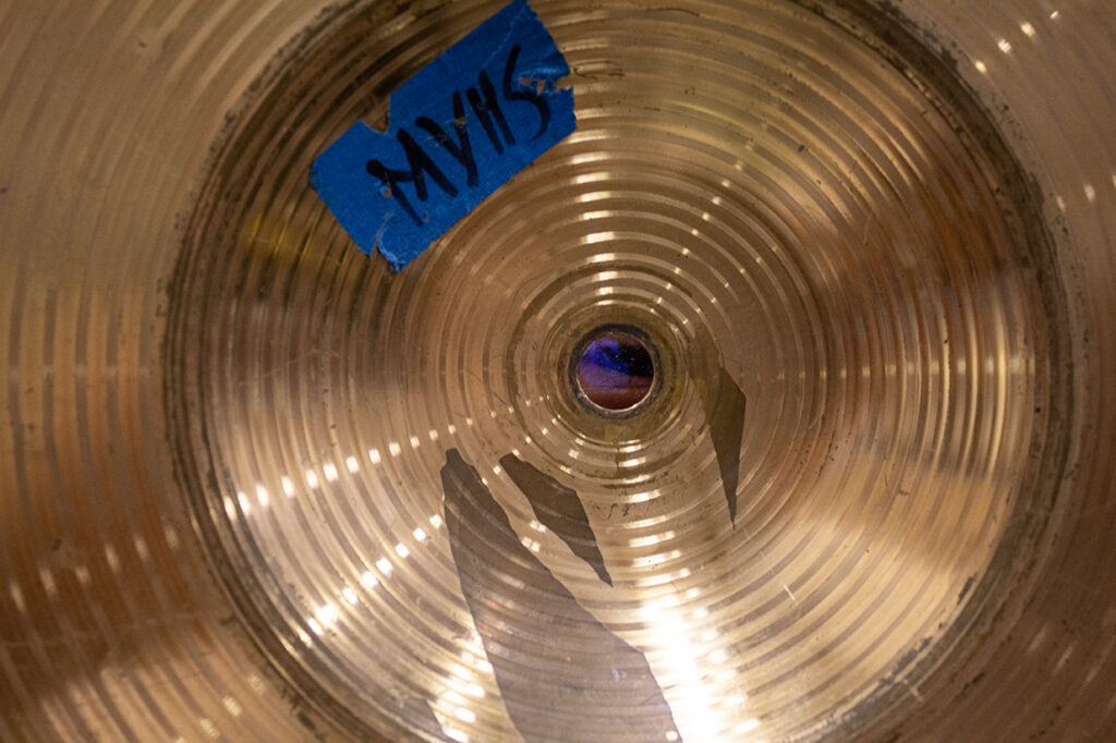 A close up of a cymbal, with an eye looking through the hole in the center.