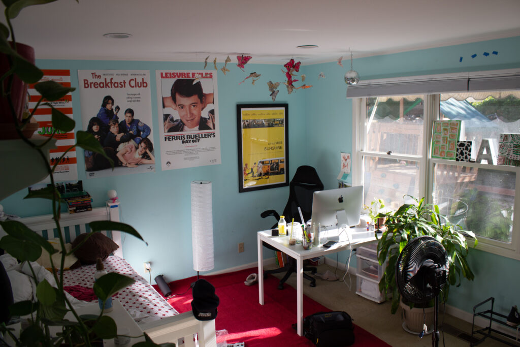 A photo of my room. My room has a lot of posters, my room is blue and has a red rug.