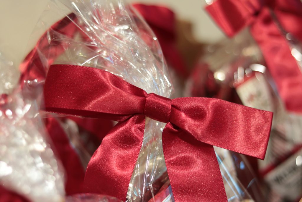 A close up photo of a plastic gift back with a large, shiny, red bow on it. 