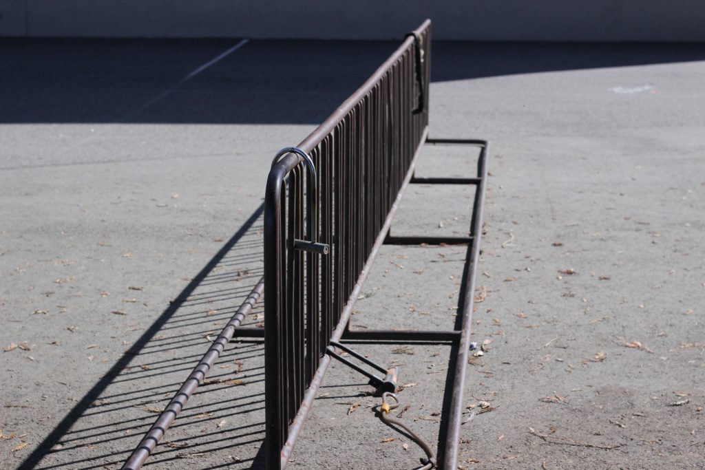 This photo shows a bike rack in the middle of the frame with a couple of locks on it. There are multiple holes in the bike rack which helps portray leading lines.