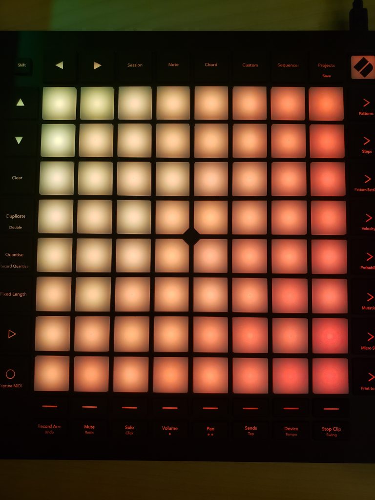 This photo shows an audio Launchpad, and it is lit up with several colors. It is composed of many squares and rectangles which are all lit up.