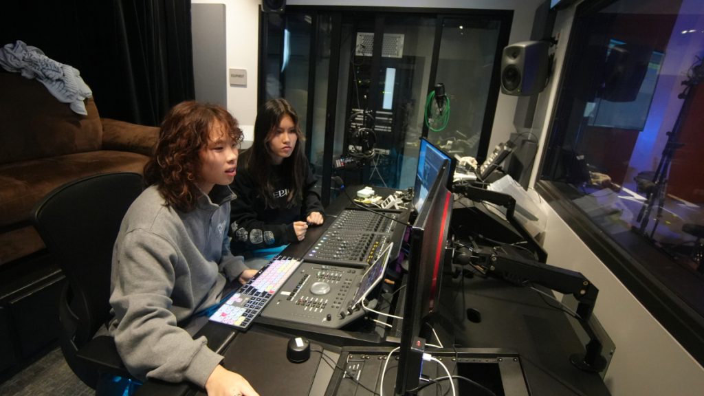 Athena Driesen and Karen Chien at the computer in the music recording booth, ready to work