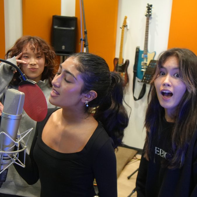 Saumya singing while Athena and Karen are being goofs behind her