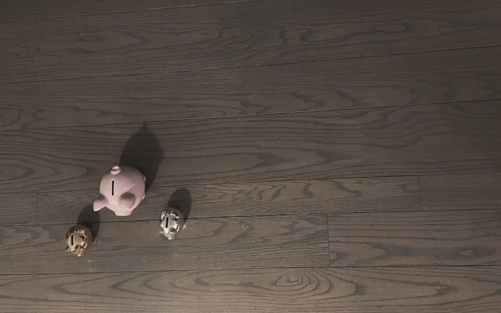three piggy banks in a desatured photo with a lot of negative space with a background as wood