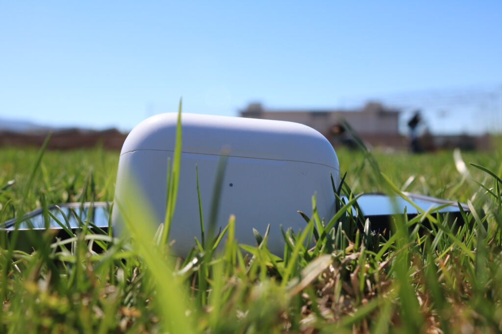 airpods in grass with iphone behind it