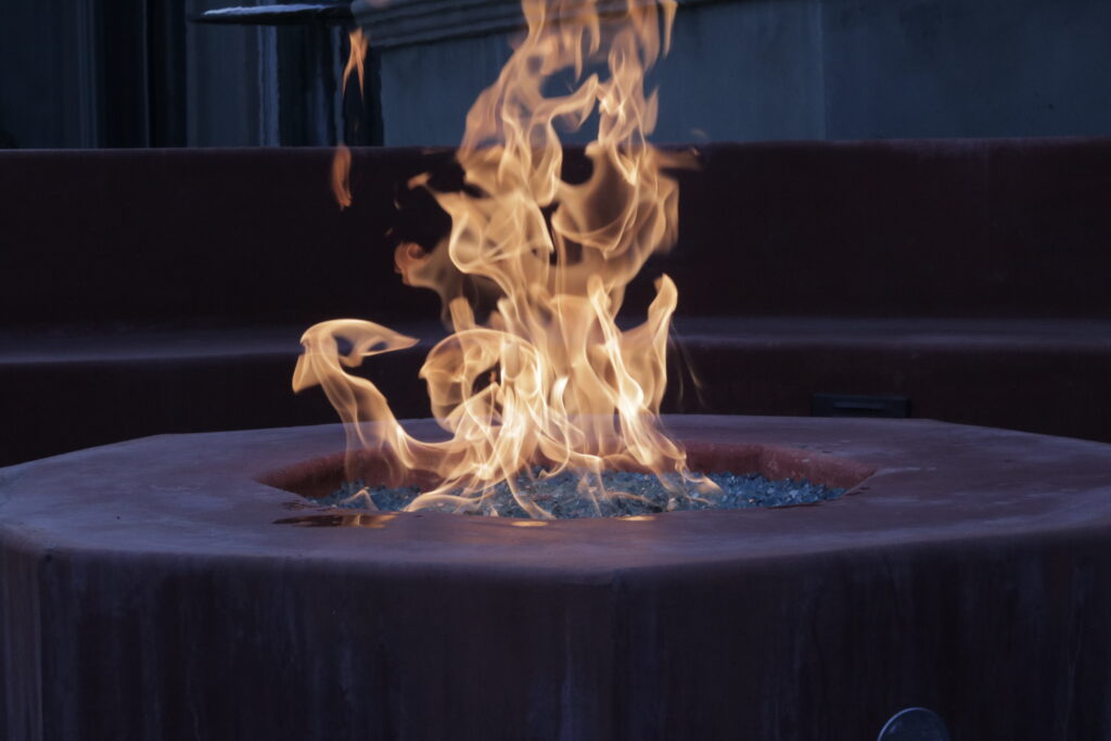 a fireplace with flames, but a cold and dark color to the whole photo almost contrasting the firepit.