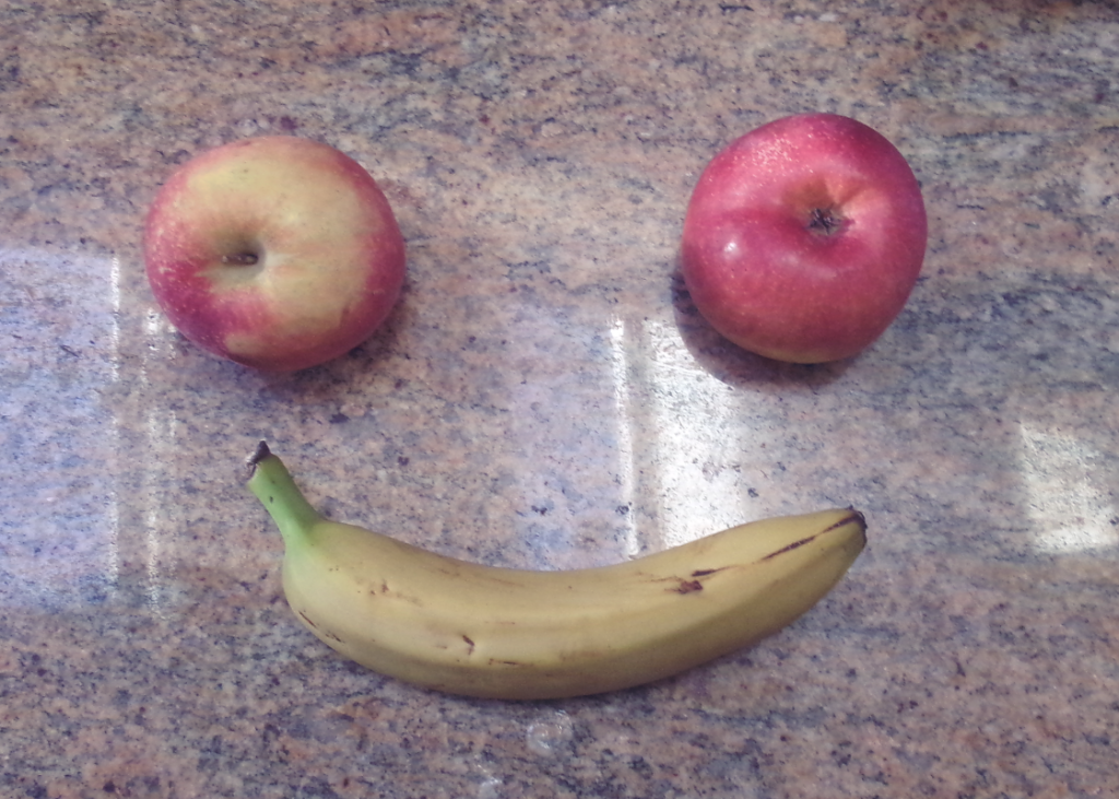 A picture of an apple and a banana placed down to create the image of a smile. 
