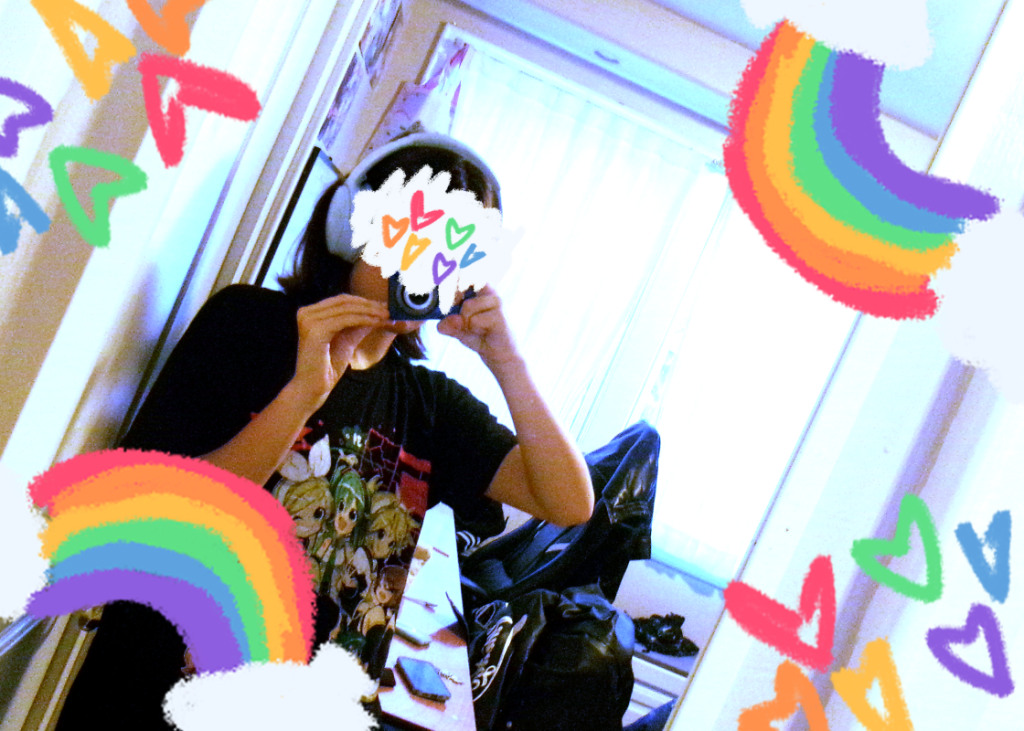 A picture of myself in the mirror with a camera, but my face and surrounding edges are decorated in rainbow chalk.