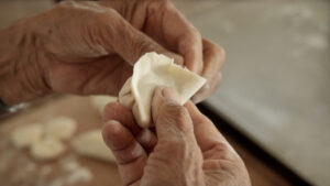 my grandma's hands folding the potstickers