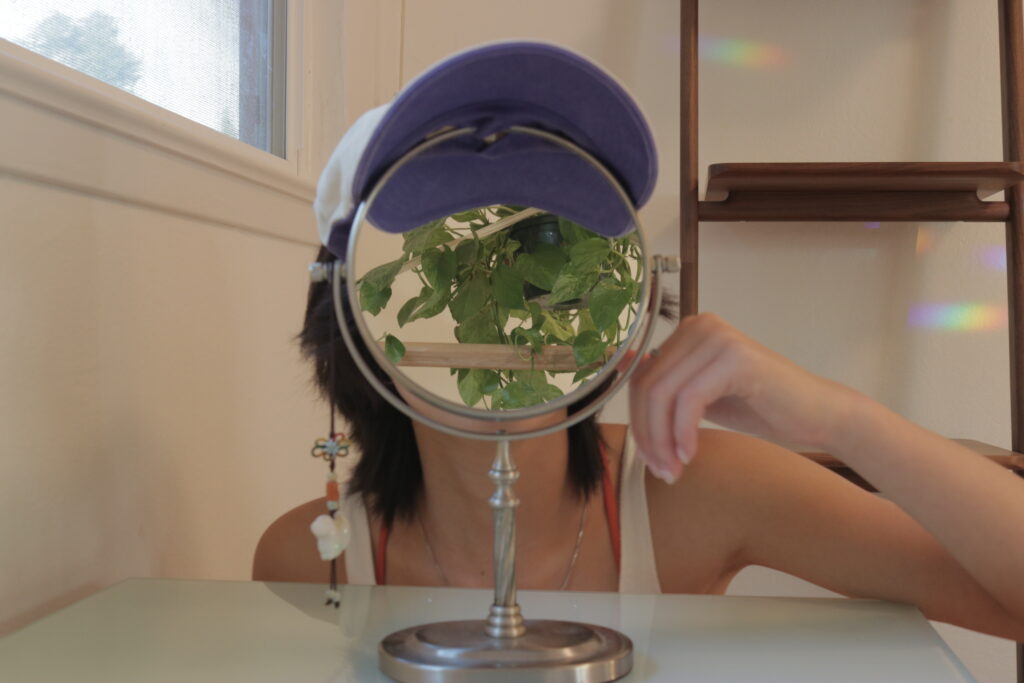 Self portrait with a mirror reflecting a plant as a face