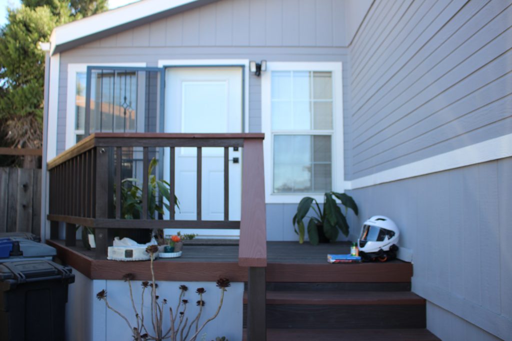 A photo of the front porch of a house with small objects (plants, books, and a motorcycle helmet) in the middleground. 