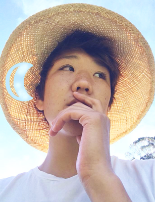 This is photo of me on a summer day. I am wearing a hat with a moon crest. It looks as tho the hole in my hat is real and you can see the clouds through it.