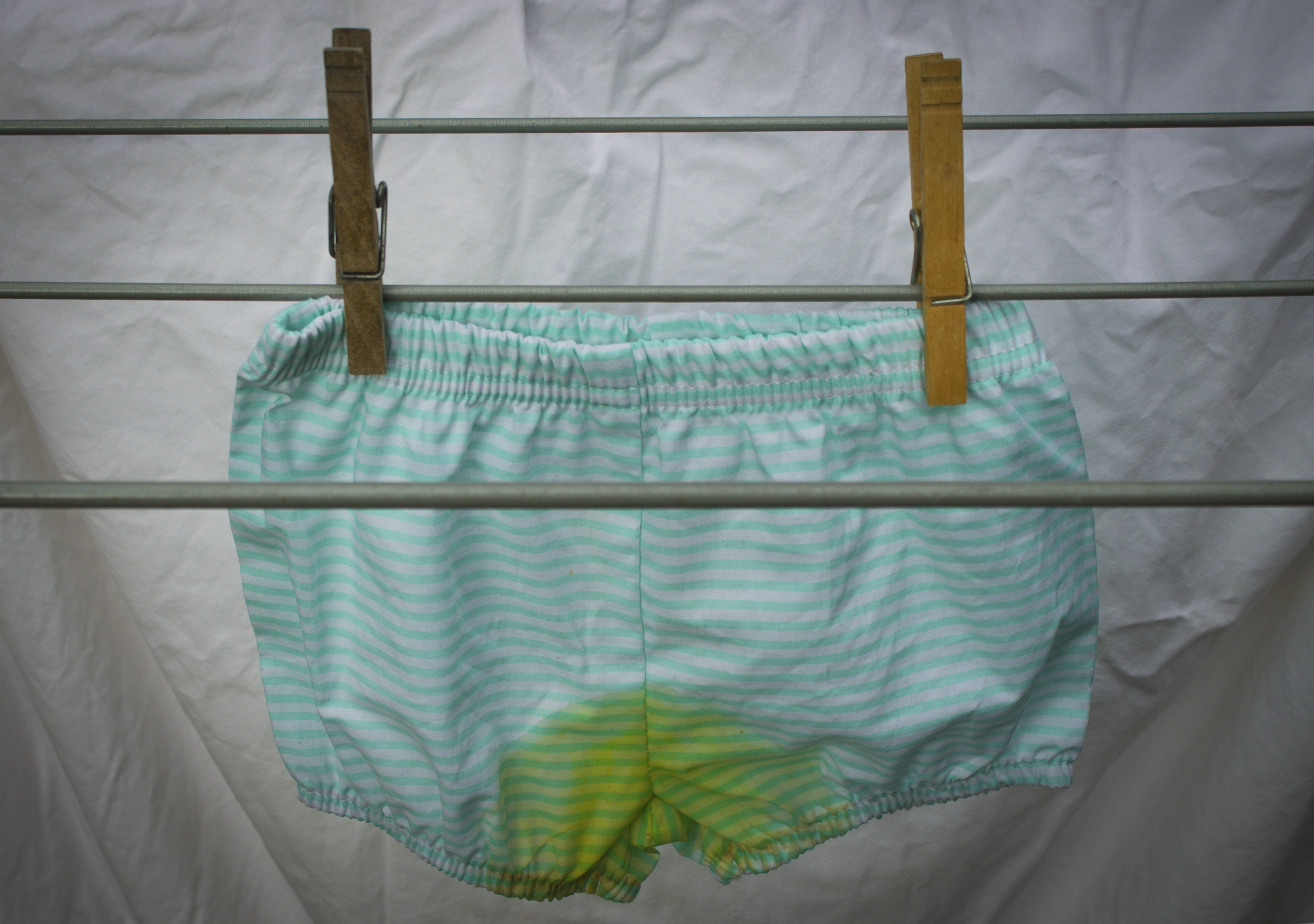 This is a phtoto of underwear stained with pee being hung on a clothesline.