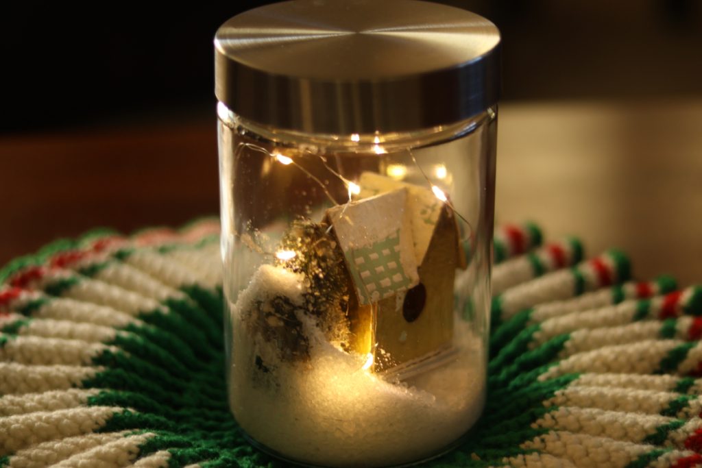 A jar with a miniature house and snow inside