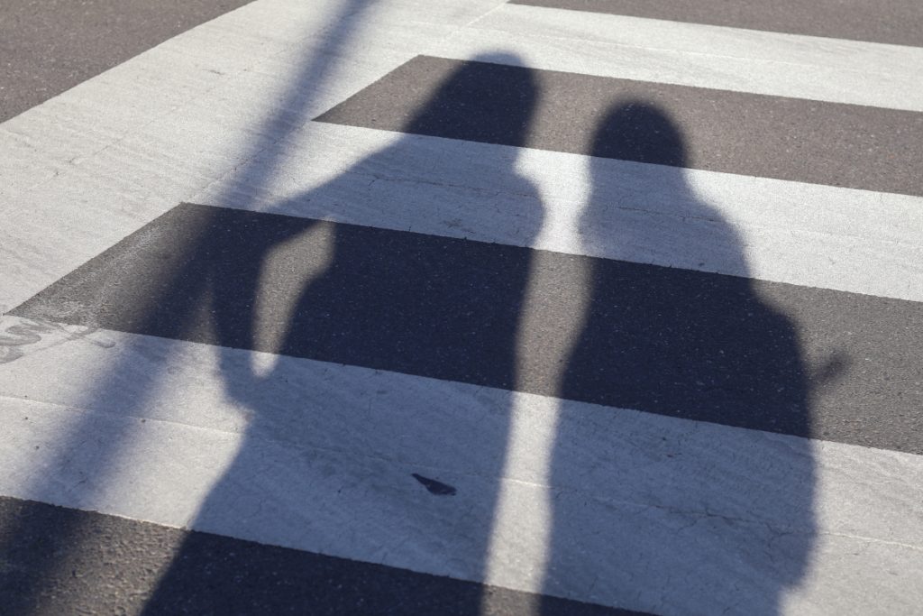 photo of a crosswalk covered by 2 shadows of people