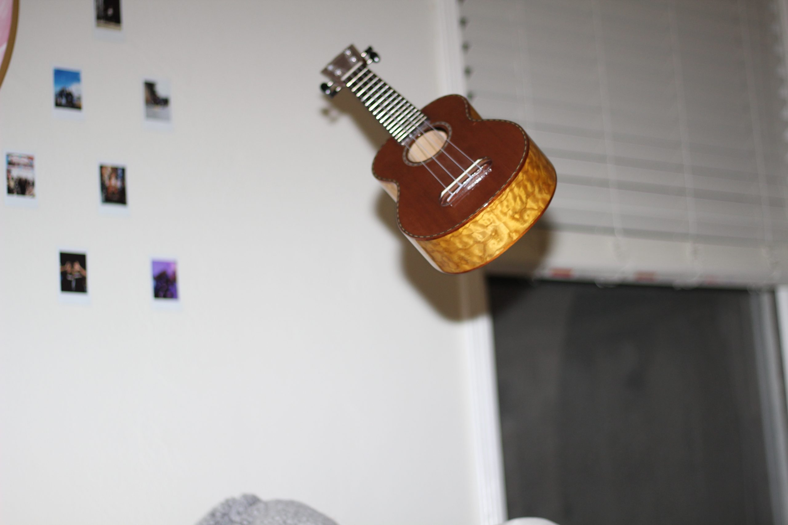 Photo of a ukulele floating in mid-air in a room. 