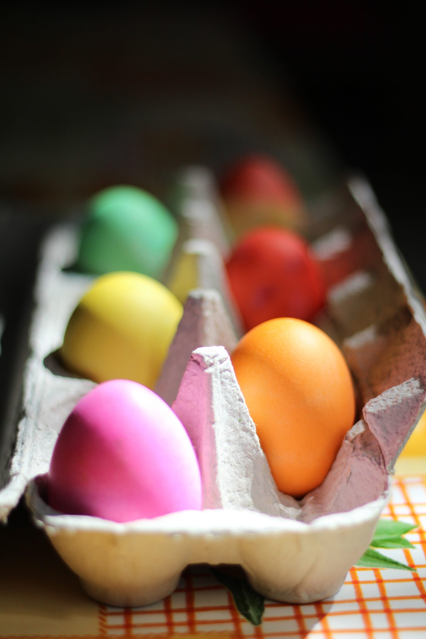 Image of easter eggs lined up in an egg carton. 