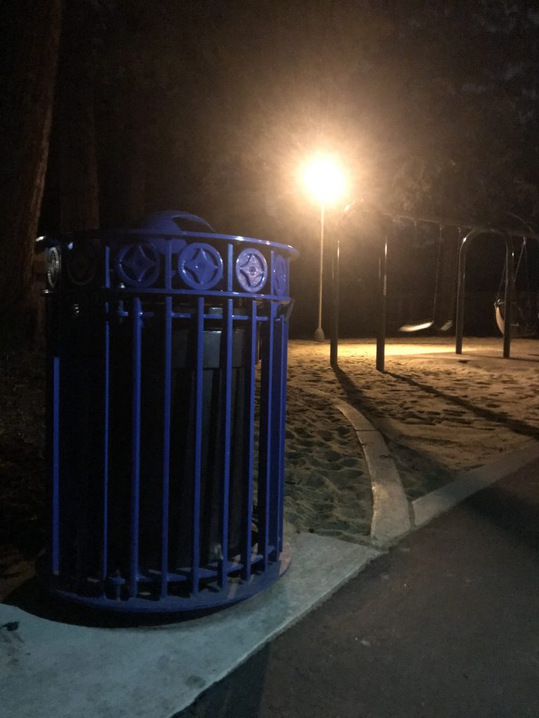 A picture of a trash can in a park.