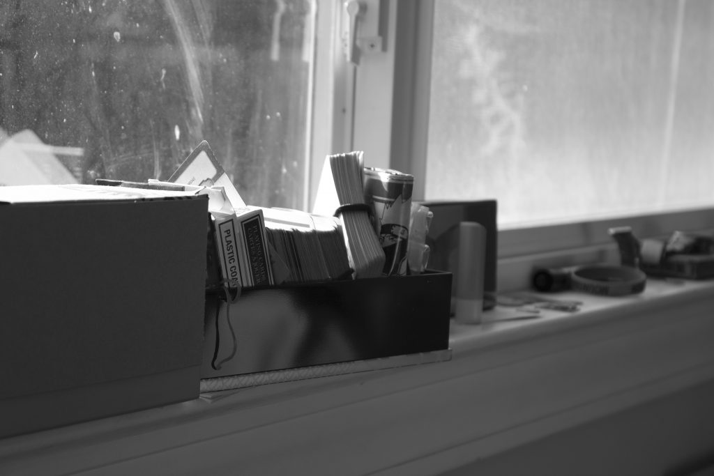 It shows a messy windowsill with cards, chapstick, a wallet, a bracelet, and other objects. There is no color in the image.