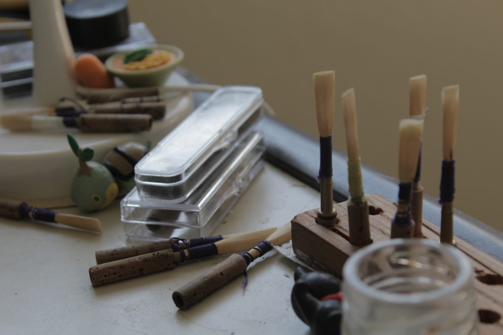 This is a picture of a corner of my desk, with reeds sprawled out away from a reed holder and erasers, as well. 
