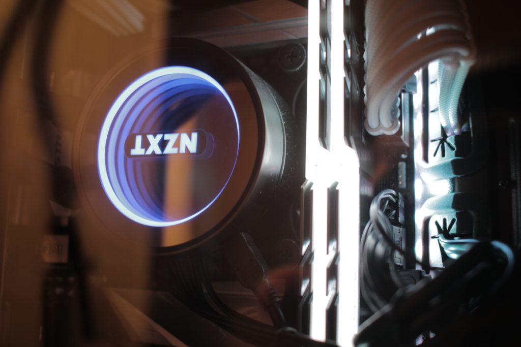 Picture showing an NZXT PC piece as well as white lighting, showing off wires and parts of a computer.