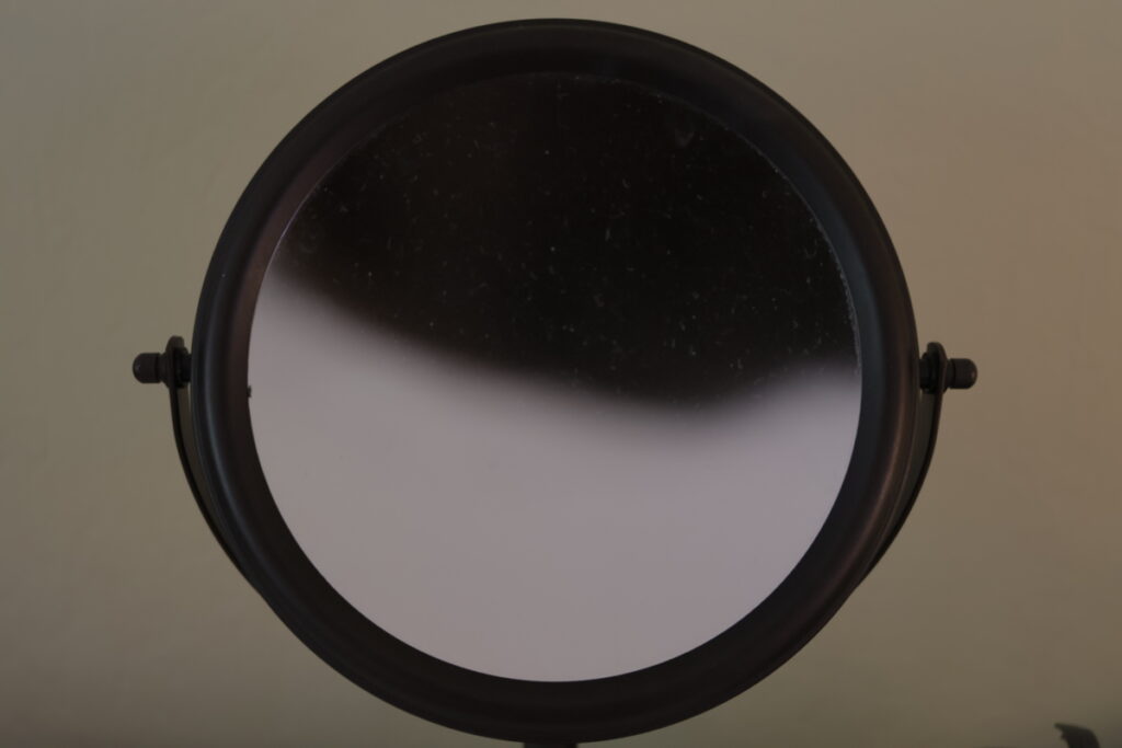 This is a closeup of my makeup mirror. The top half is dark while the bottom part is gray.