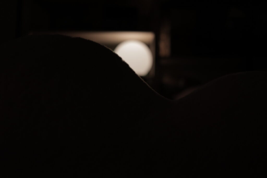 A silhouette of a pillow in front of a lamp.